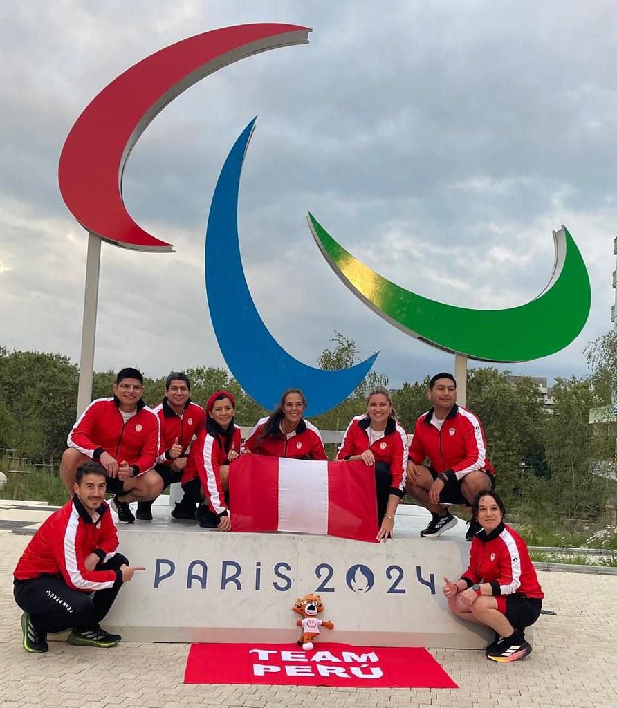 Integrantes del Team Perú posan con la bandera peruana frente al símbolo paralímpico en París