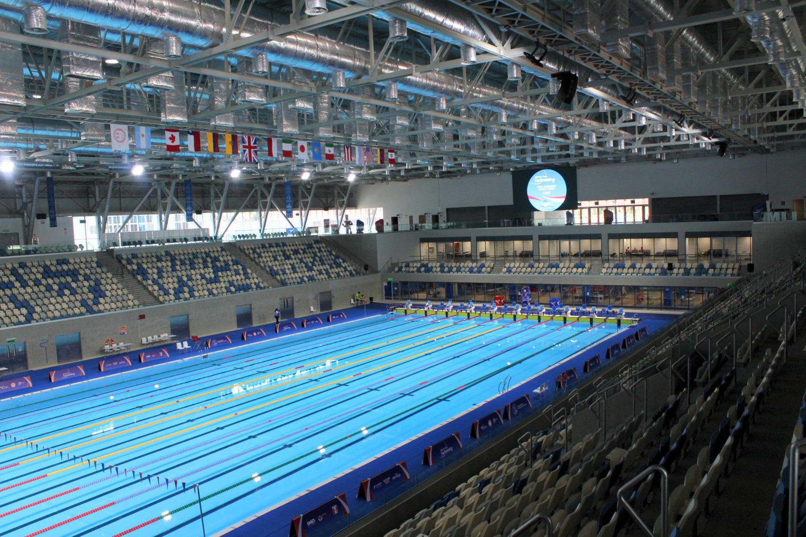 Vista general de la piscina olímpica del Centro Acuático de la Videna, con tribunas y banderas